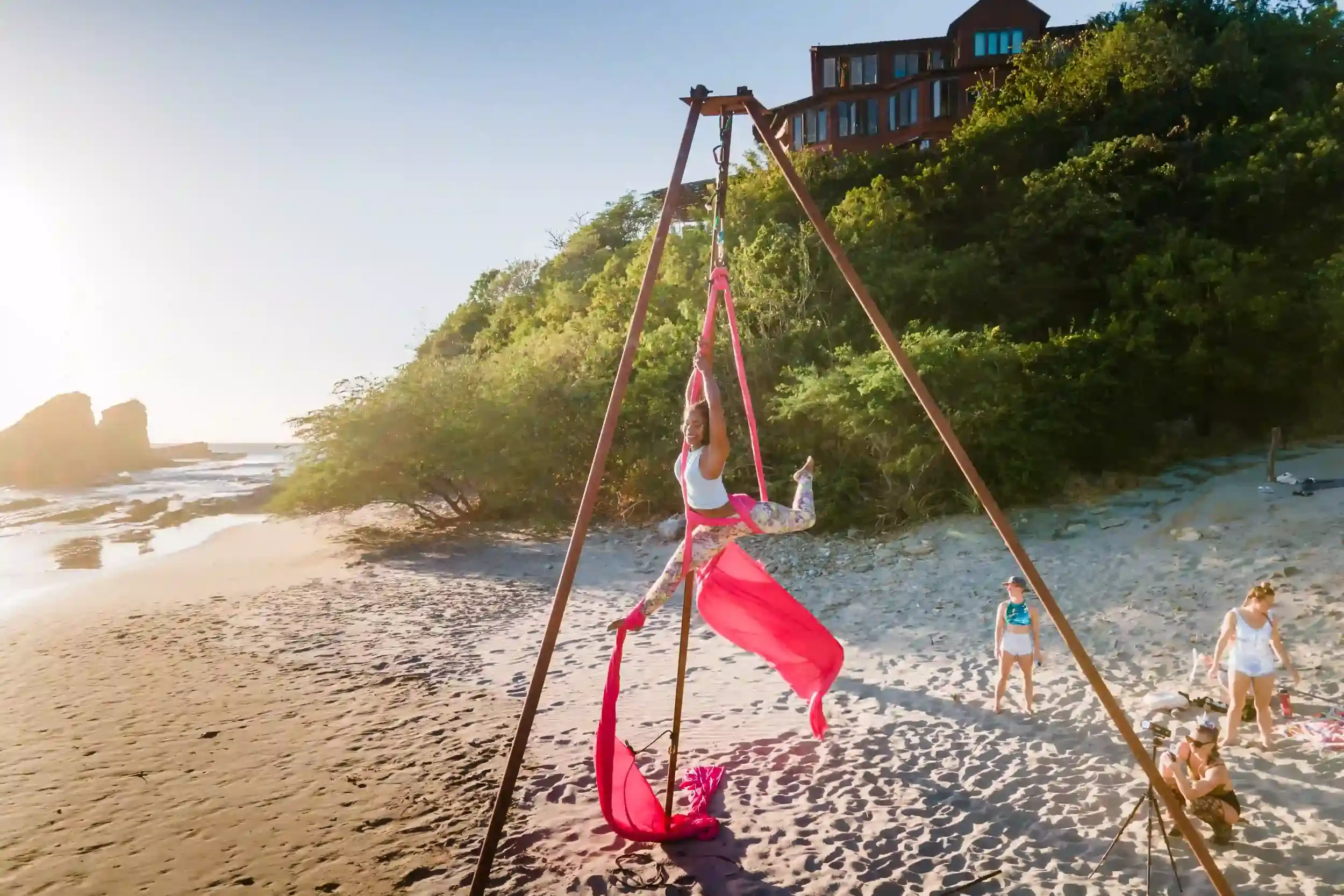 Aerial yoga platform set on the beach at Magnific Rock in Popoyo, Nicaragua, with a practitioner performing aerial poses above the sand