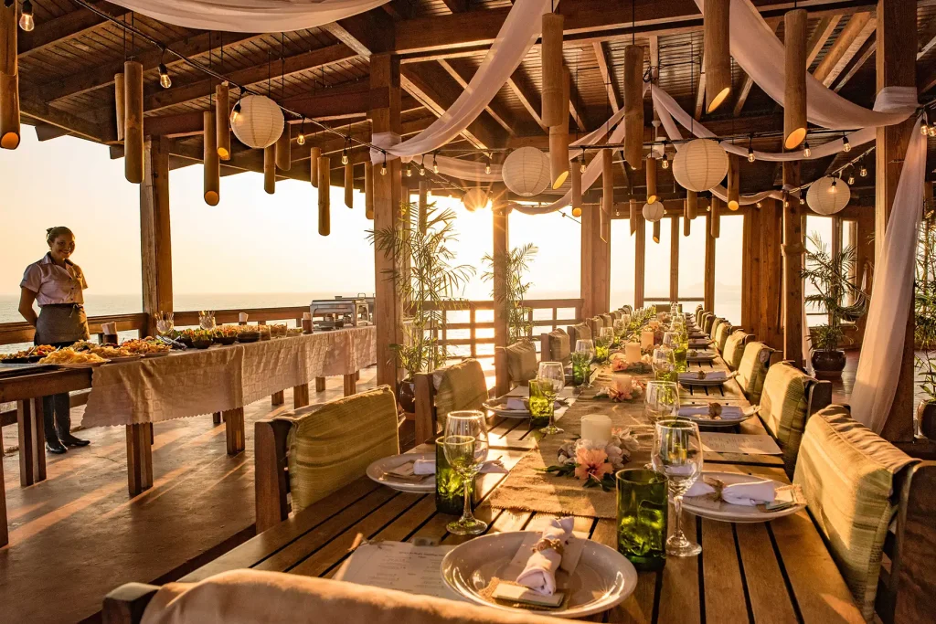 wedding reception setup on the clifftop terrace at Magnific Rock with Pacific Ocean views at sunset